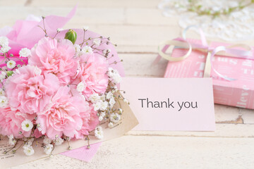 カーネーションとカスミソウの花束とプレゼントに添えられたサンキューカード