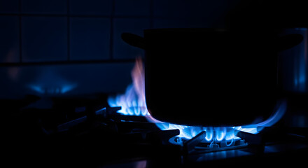 A large pot being heated intensely on a gas stove burner with blue flames in a kitchen environment
