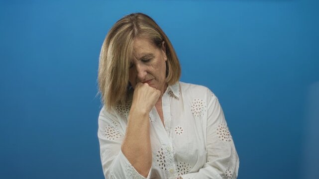 Woman wearing white blouse with hand on chin in studio setting showing closed eyes expression; contemplation.