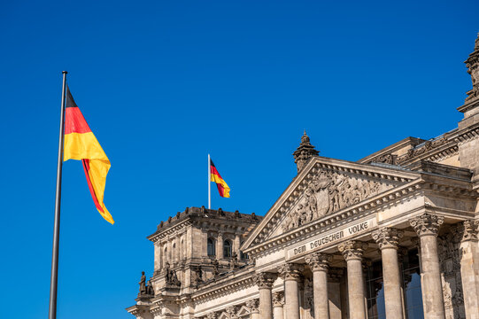 Berlin, germany, august 15, 2023. Reichstag facade with german flags flying under a clear blue sky, symbolizing germany's federal parliament, democracy and heritage