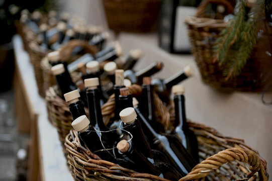 Wicker baskets with dark glass bottles on wooden shelf with light snow