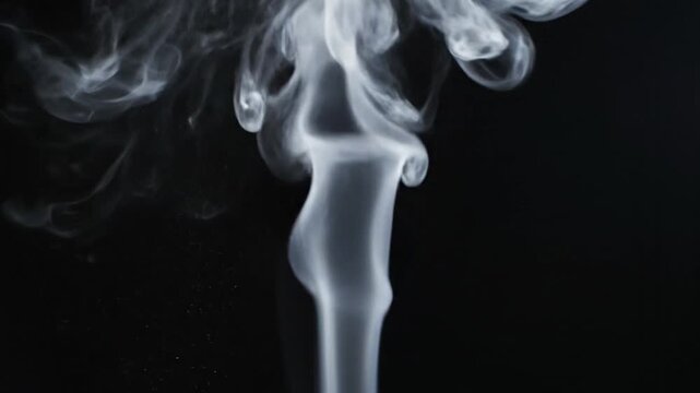 Close-up shot of rising smoke against a dark background with a moody atmosphere.