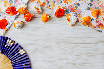 木目背景に桜の花と青い扇子や色とりどりの貝殻をあしらった明るい和の空間を演出するお祝いの背景素材