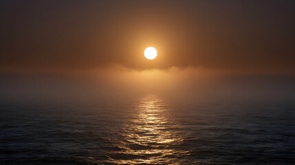 A bright sun shines through atmospheric mist over the calm ocean at dusk casting a shimmering reflection