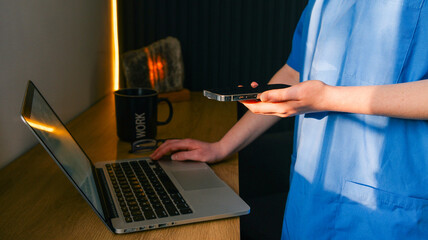 Healthcare professional using laptop and smartphone for medical tasks