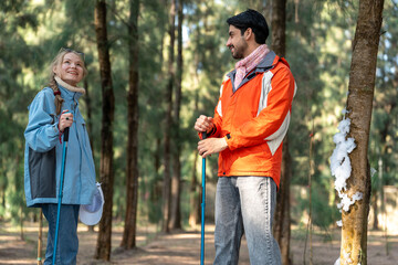 Fototapeta premium Couple in Hiking Gear Having Serious Conversation in Winter Forest – Man and Woman Facing Each Other with Trekking Poles in Hand under Snowy Pine Trees, Natural Light, Tension Scene