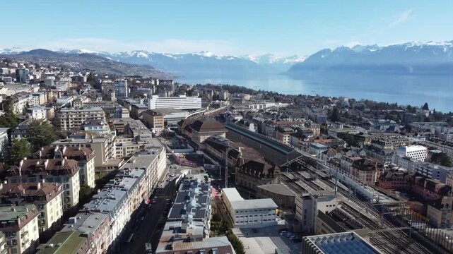 Drone flying toward Lausanne train station with Lake Geneva and Alps