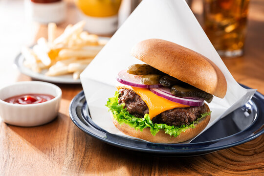 ワックスペーパーに包まれたチーズバーガーとフライドポテトとコーラ