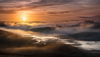 Fototapeta premium Golden light illuminates misty valley landscape with lake and rolling hills at sunrise