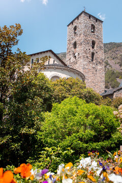Exterior of St Esteve of Andorra Church with a garden and Pyrenees mountains in the background in Andorra la Vella old town on a sunny day