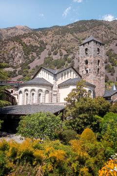 Exterior of St Esteve of Andorra Church with a garden and Pyrenees mountains in the background in Andorra la Vella old town on a sunny day