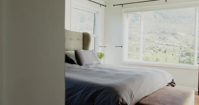 Camera is pushing right from doorway, revealing tufted headboard, grey bed and showing room layout