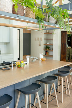 kitchen island is featuring wood top, citrus bowl, glass jars, four black stools in modern kitchen