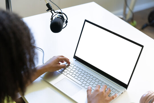 Silver laptop displaying blank white screen and condenser microphone hovering on boom arm at desk