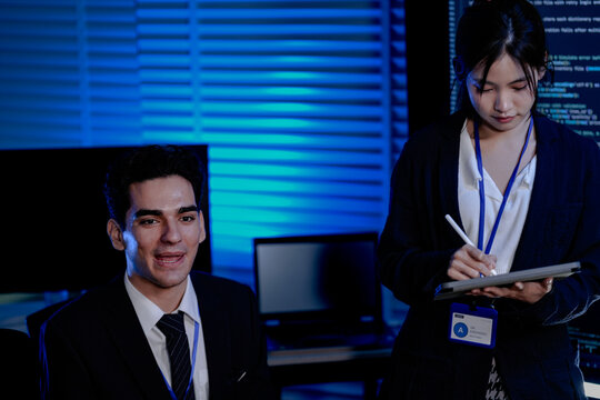 An Indian female developer leads a code review, holding a report. She explains a Python script for an AI or cybersecurity system to her team in a dark SOC Security Operations Center