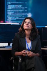 A professional Indian businesswoman smiles while sitting in a high-tech office. She is engaged in a...