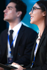 A young, happy Caucasian businessman in a suit and tie smiles while listening intently. He is...