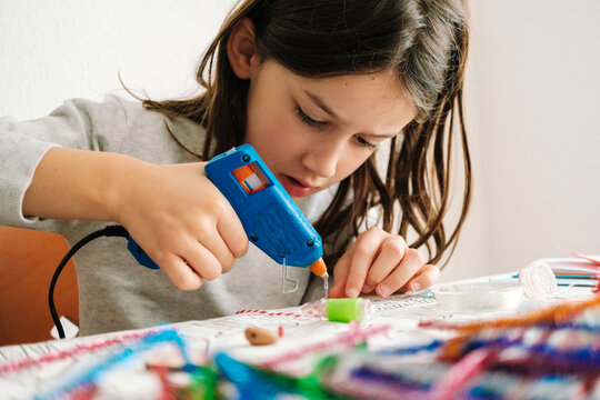 Student working on crafts with glue gun during school activity in classroom