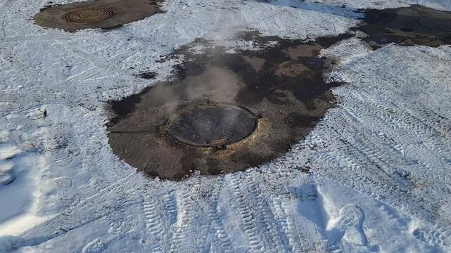 Steam rises from manholes on a winter city street.