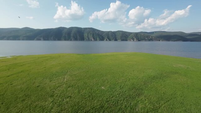 A lake in a national park in summer, birds flying over the water, filmed with a drone
