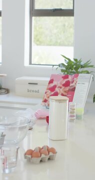 Vertical video: Camera panning across kitchen counter showing white canister eggs bowl for baking