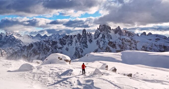 Aerial footage of a ski mountaineer in a snowy alpine ridge in Dolomites. Winter landscape, backcountry adventure, and solitude in breathtaking mountain scenery captured in 4K.