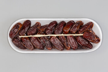 Dried dates on foam tray on gray background, top view