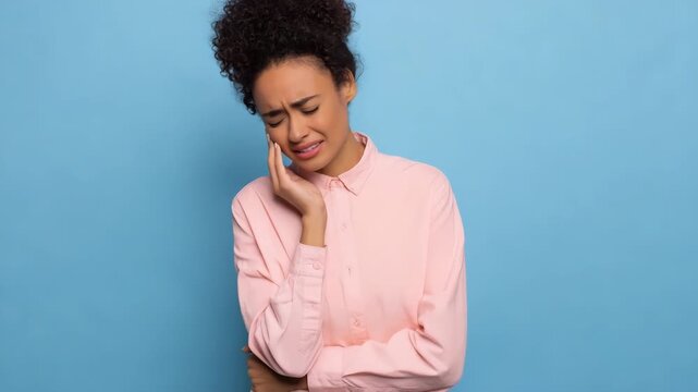African female experiencing toothache in pink shirt against blue background