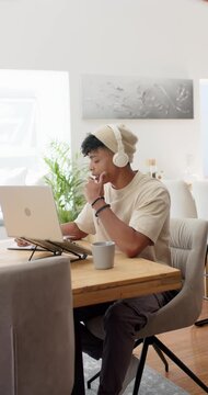 Vertical video: African American man adjusting headphones, using tablet and laptop for work