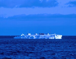 Obraz premium Large iceberg with structures on floating in deep blue ocean under cloudy sky water