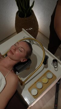 Skilled hands gently cleanse a woman's face with a wet cloth during a spa treatment
