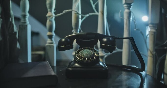 Woman shining flashlight on old rotary phone then slowly picking it up in spooky home, closeup
