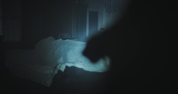 Creepy, over the shoulder shot of person with flashlight shining it on spooky, covered up room