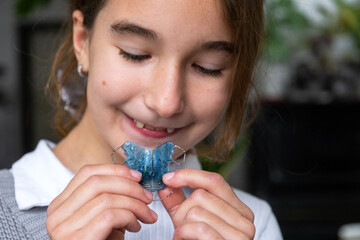 Pediatric bite correction: girl age 9 showing her removable orthodontic plate before putting it in. © Ольга Симонова