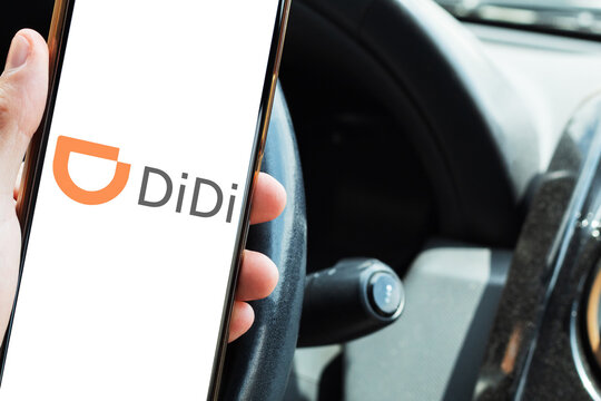 Driver checking the DiDi app on a smartphone from inside the car. On-demand transportation and collaborative economy