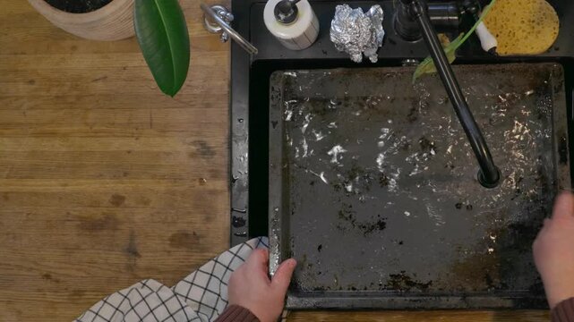 Top view of man cleaning and preparing fresh fish in black kitchen sink. Home seafood preparation process before cooking, everyday kitchen routine and food preparation concept