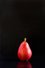 Beautiful Wet Red Pear on Wet Black Background with Lots of Empty Space