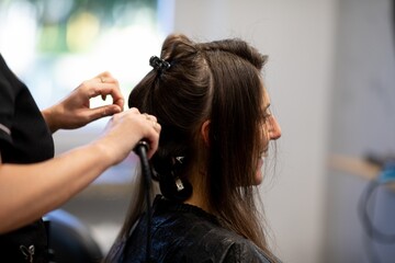 Naklejka premium Calm atmosphere during hair styling process, Closeup of stylist working on damp hair in salon, Candid scene showing stylist carefully braiding damp hair with warm lighting