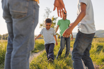 Fototapeta premium Single father walks with his two sons in a green field as they share joyful moments during sunset.