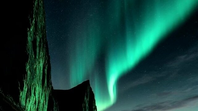 Bright green light danced vertically across the star-studded night sky, creating a dramatic contrast with the sharp, dark silhouettes of the rocky cliffs.
