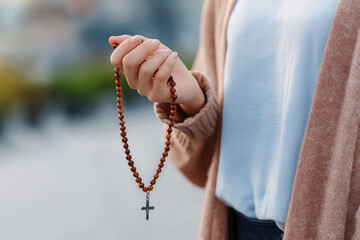 Holding a wooden rosary in a serene outdoor setting