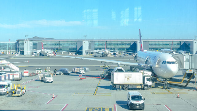 Busy airport terminal with multiple aircraft parked at gates, ground crew servicing planes, showcasing aviation operations and travel atmosphere
