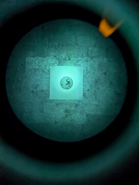 View Through Night Vision Device Optic Showing Paper Shooting Target with Bullet Holes on Stone Wall During Tactical Training Session
