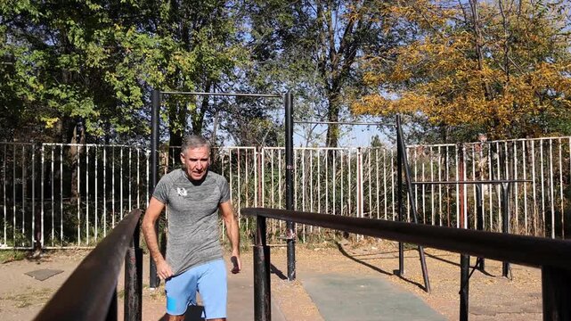 Strong Senior Male Doing Parallel Bar Dips - Calisthenics Park - Street Workout. Series Track Code: Fit-Mature-Man-54-Outdoor-Fitness-Series-2024