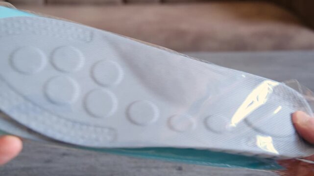 Male hands unpack gray shoe insoles. Soft orthopedic insoles for sneakers. Comfortable footwear for sports activities.