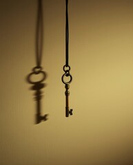 Key hangs from a string on wall casting shadow in a dimly lit space during evening hours