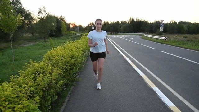 Young woman starting to run and accelerating forward at sunset. Slow motion shot captures powerful first strides and dynamic urban fitness atmosphere. Ideal for new beginnings, motivation, and perform