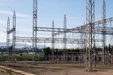 Fototapeta premium Pamplona, Spain - February 23, 2026. An open-air electrical substation, with multiple metal lattice structures, suspended cables, insulators and high-voltage equipment, located in an industrial area 