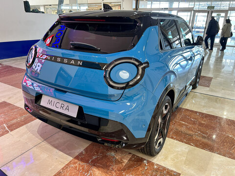 Pamplona, ​​Spain - February 23, 2026. A blue compact car, Nissan Micra model, displayed inside a dealership, with modern design, circular lights and details in glossy black.