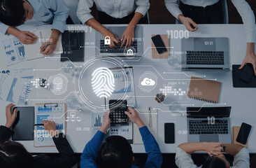 A diverse team collaborates around a modern office table, utilizing laptops and technology to...